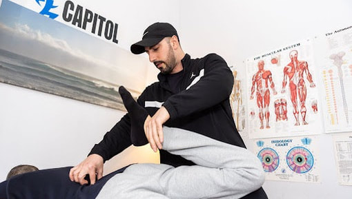 Muscle activation specialist working on a client's leg in the treatment room
