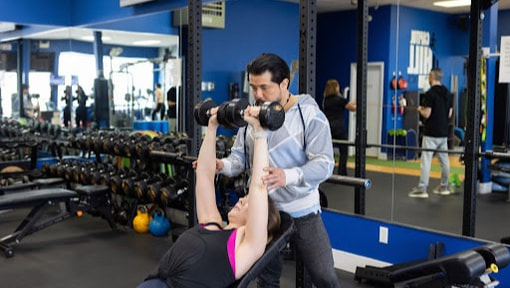 Trainer spotting a client during a dumbbell press at Capitol Hill Athletics